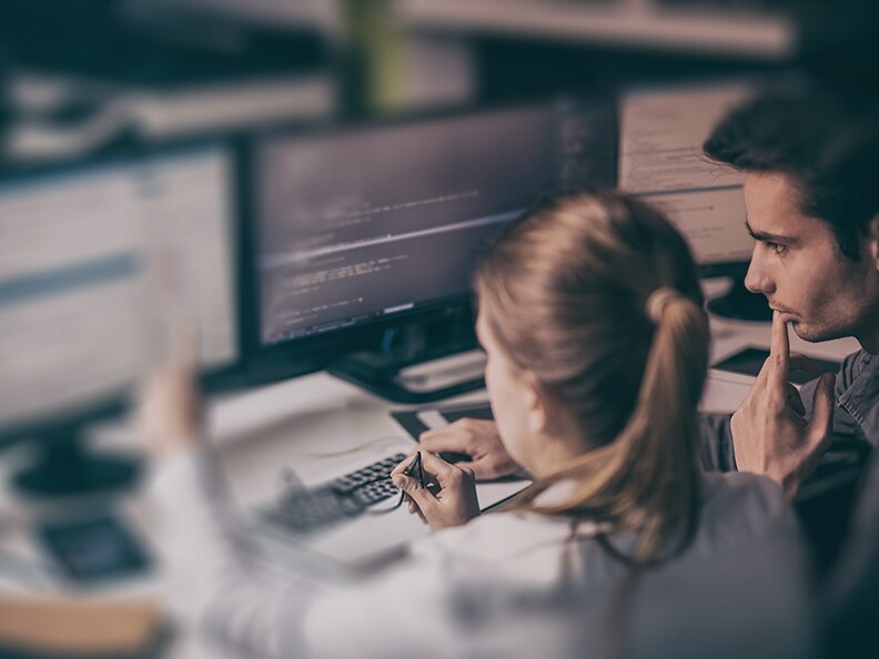 A man and woman review the results of the Unit 42 BEC Readiness Assessment on their computer monitors.